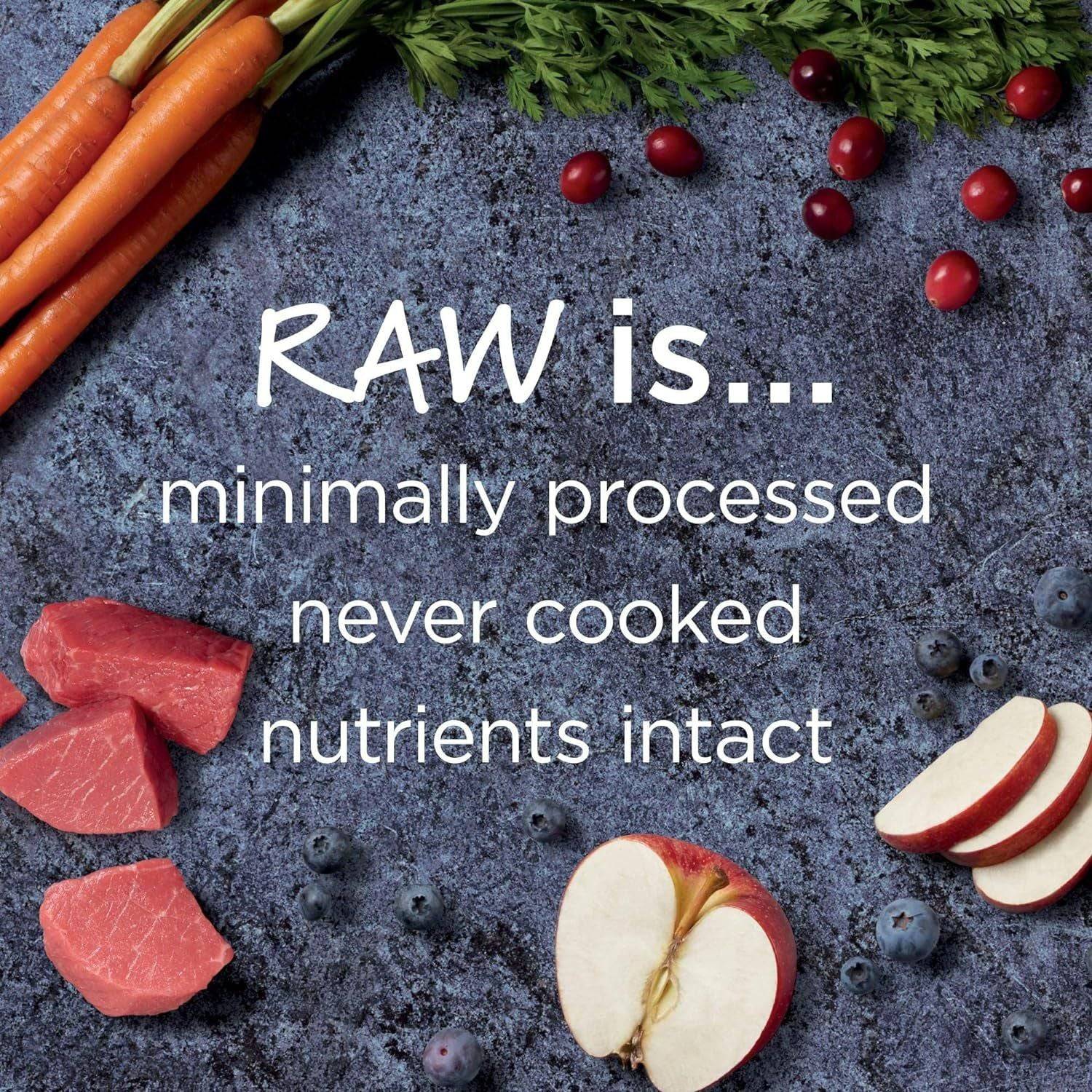 Image showing various raw foods on a textured, dark background. Includes fresh carrots with greens, sliced red meat, cranberries, blueberries, and slices of red apple. Text overlay reads "RAW is... minimally processed, never cooked, nutrients intact" in white modern font.