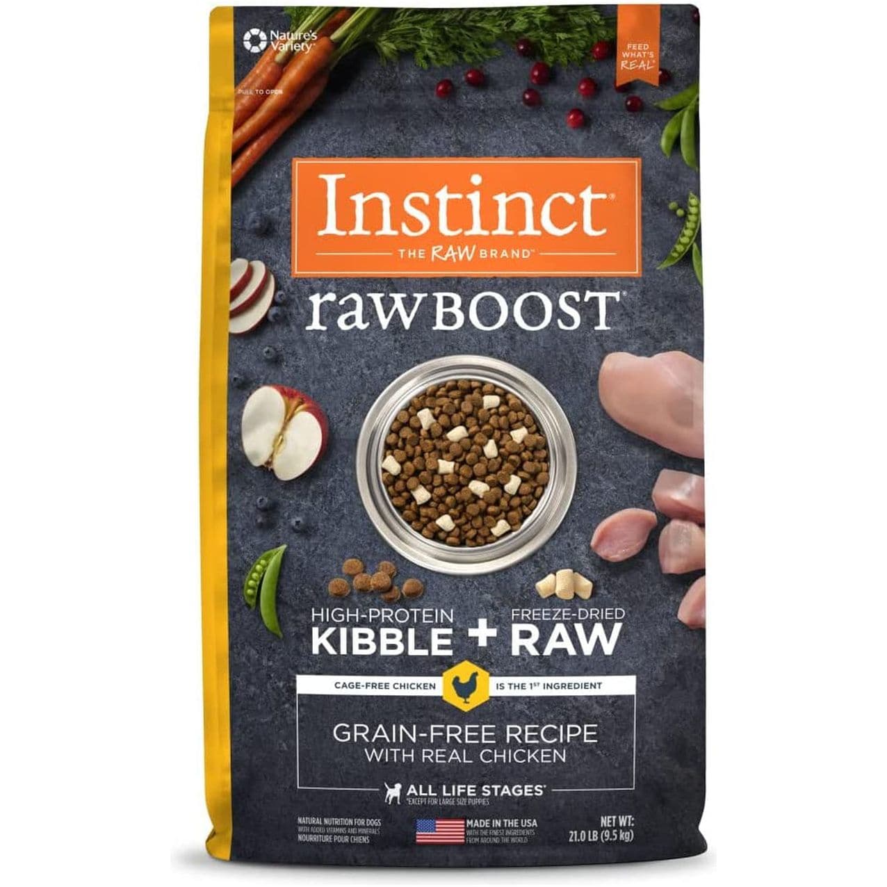 A package of Instinct Raw Boost high-protein dog food featuring cage-free chicken as the main ingredient. The package displays a bowl of kibble surrounded by fresh carrots, parsley, radish slices, and nuts on a dark stone background. Text includes product details such as 'Grain-Free Recipe' and 'Made in the USA.'