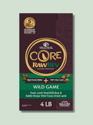 A bag of Wellness Core RawRev Wild Game high-protein, grain-free dog food with a recipe of duck, lamb meal, wild boar, and rabbit with freeze-dried lamb, weighing 4 pounds. The packaging is brown with gold and green accents and a circular logo at the top.