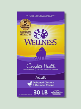 A purple and yellow bag of Wellness Complete Health Natural Food for Adult Dogs with deboned chicken and oatmeal recipe, weighing 30lbs and made in the USA.