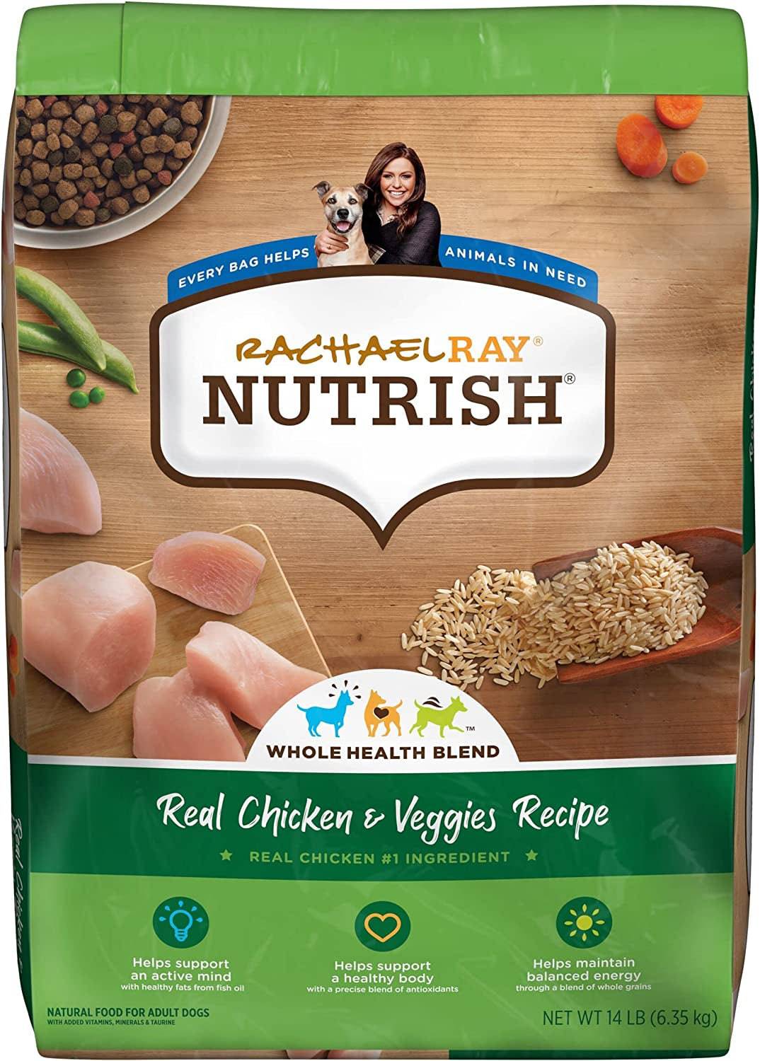 A bag of Rachael Ray Nutrish Real Chicken and Veggies Recipe dog food with the images of raw chicken pieces, whole grain brown rice, a dog bowl filled with kibble, and scattered peas and sliced carrots on a wooden surface. The package has a green top and branding details in white, orange, and brown colors emphasizing natural food for adult dogs, supporting an active mind and a healthy body with antioxidants. There is also an icon indicating that every bag helps animals in need.