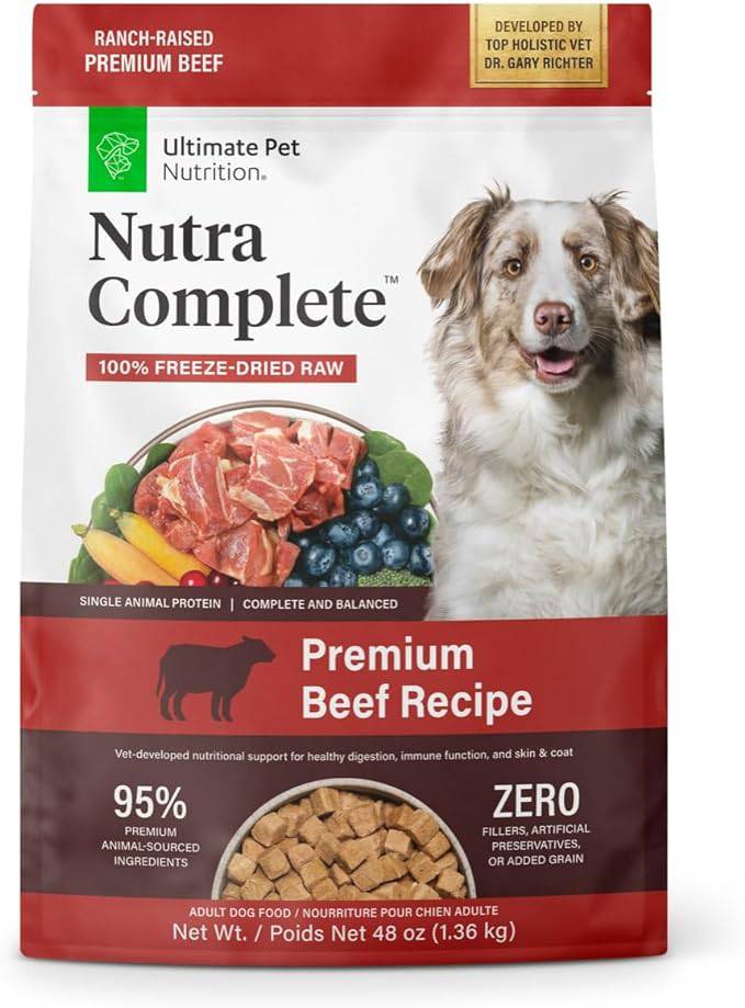 A bag of Nutra Complete Ultimate Pet Nutrition premium beef dog food, stating it is 100% freeze-dried raw with single animal protein and no fillers, artificial preservatives, or added grain. The package has images of raw beef chunks and blueberries at the top, and the lower section shows a bowl of the kibble. The dog food is advertised as vet-developed for nutritional support for healthy digestion, immune function, and skin and coat, with 95% premium animal-sourced ingredients.