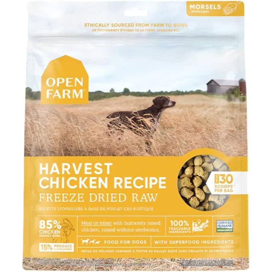 A package of Open Farm Harvest Chicken Recipe dog food featuring a field with a dog lying in tall, golden grass, the product advertised as freeze-dried, raw chicken suitable for dogs, highlighted with claims of 85% chicken content, ethical sourcing and additional health benefits.