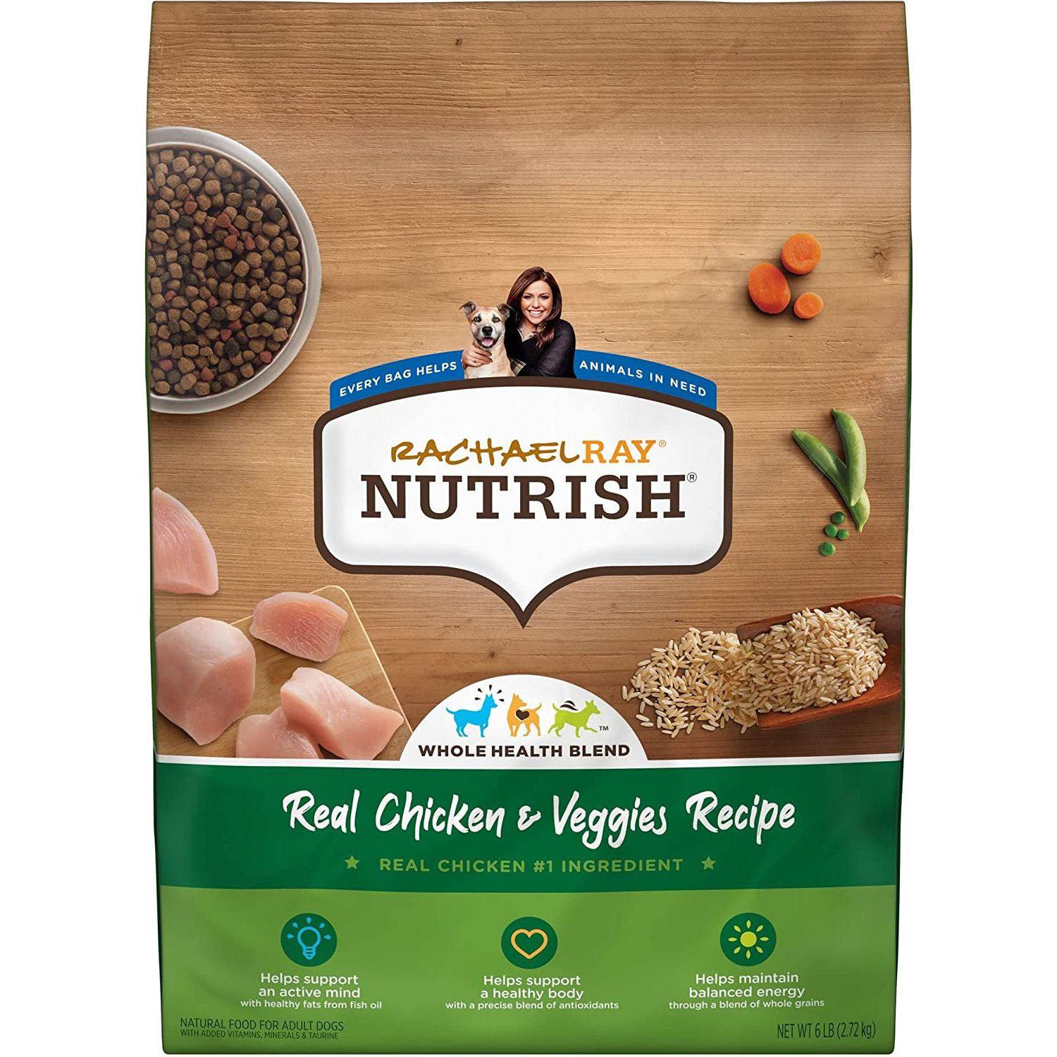 A bag of Rachael Ray Nutrish Whole Health Blend with Real Chicken & Veggies Recipe natural food for adult dogs is displayed against a wooden background. The packaging features images of sliced chicken, carrots, peas, and grains to represent the ingredients. It promotes healthy minds with active nutrients and balanced energy through whole grains. The label on the package states that every bag helps animals in need.