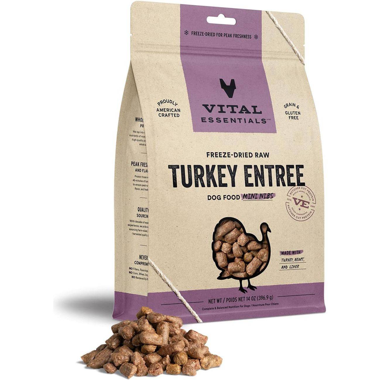 A package of Vital Essentials freeze-dried raw turkey entree dog food, with a label showing its grain and gluten-free quality, and a heap of kibble spilled in front of it.