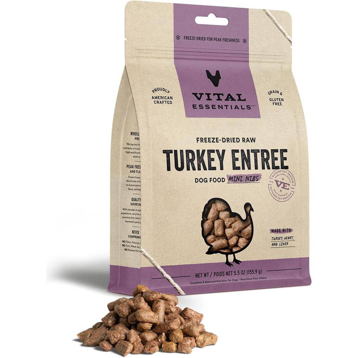 A bag of Vital Essentials freeze-dried raw turkey entrée dog food mini nibs, with the product spilling out in front onto a white background. The packaging features text and logos indicating it's grain-free and made with turkey heart and liver.